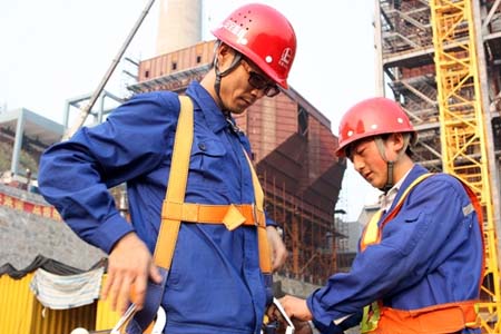 進入高空作業(yè)前，同事正在幫他穿戴高空安全帶
